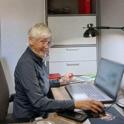 Dr. Ute Wunnike sitzt lächelnd an ihrem Schreibtisch am Laptop